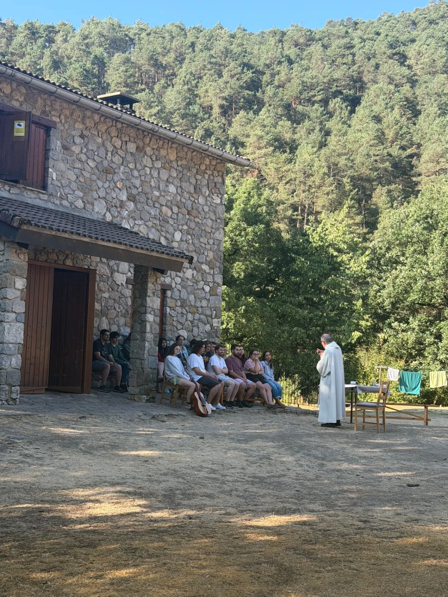 Missa a l'aire lliure amb els joves davant d'una casa de pedra